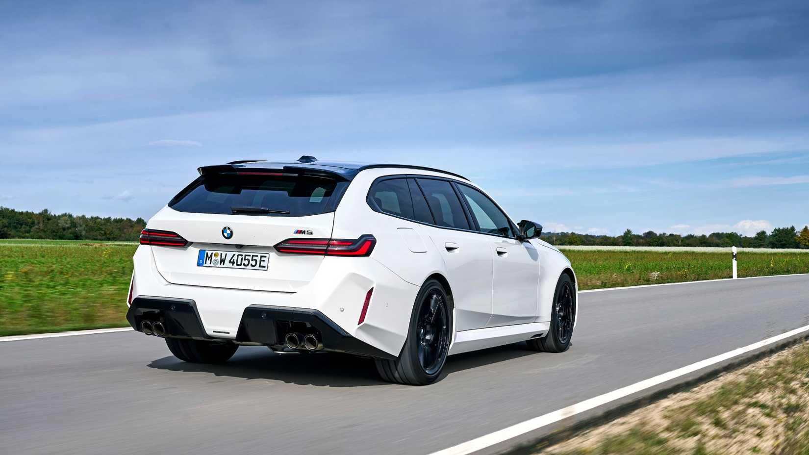 Dynamic rear 3/4 shot of a white BMW M5 Touring.