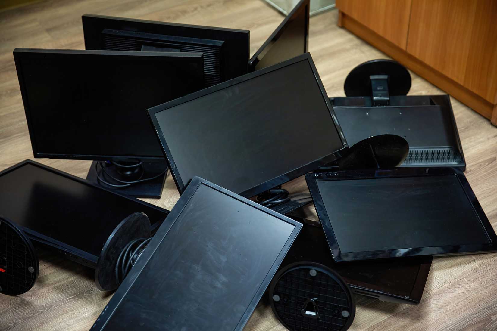 Black, old, dusty, computer monitors in a pile.