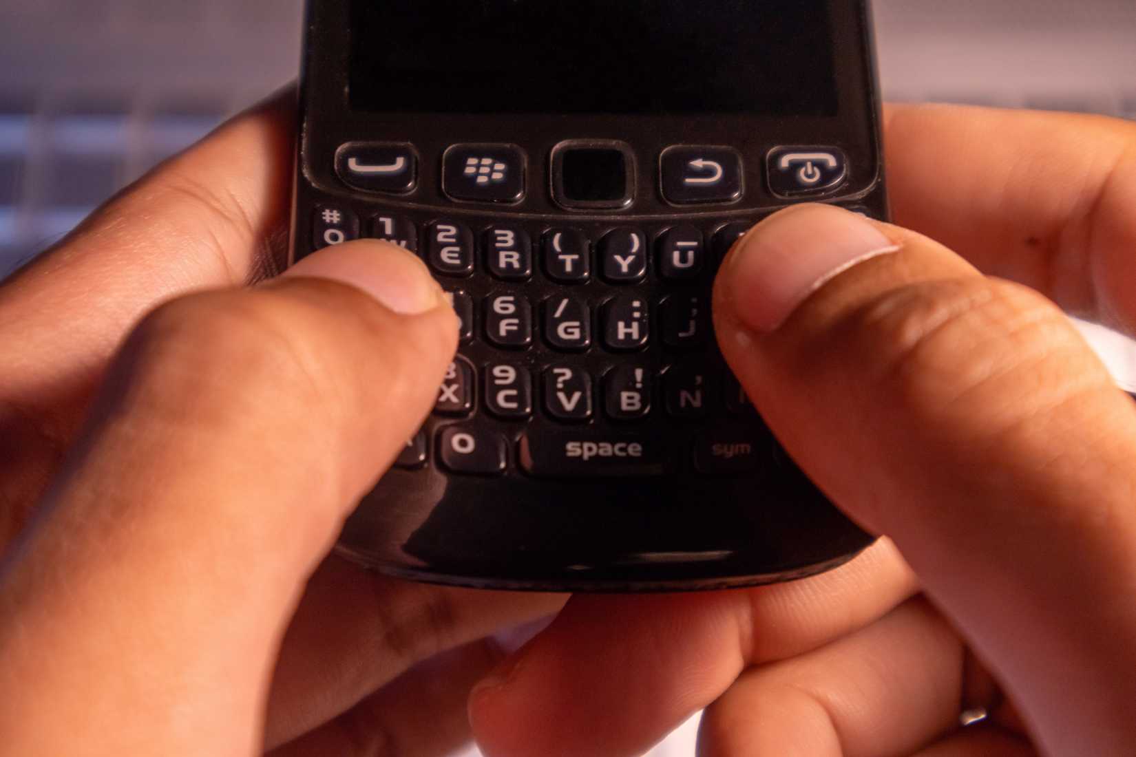 A person operating a Blackberry keyboard with their thumbs.