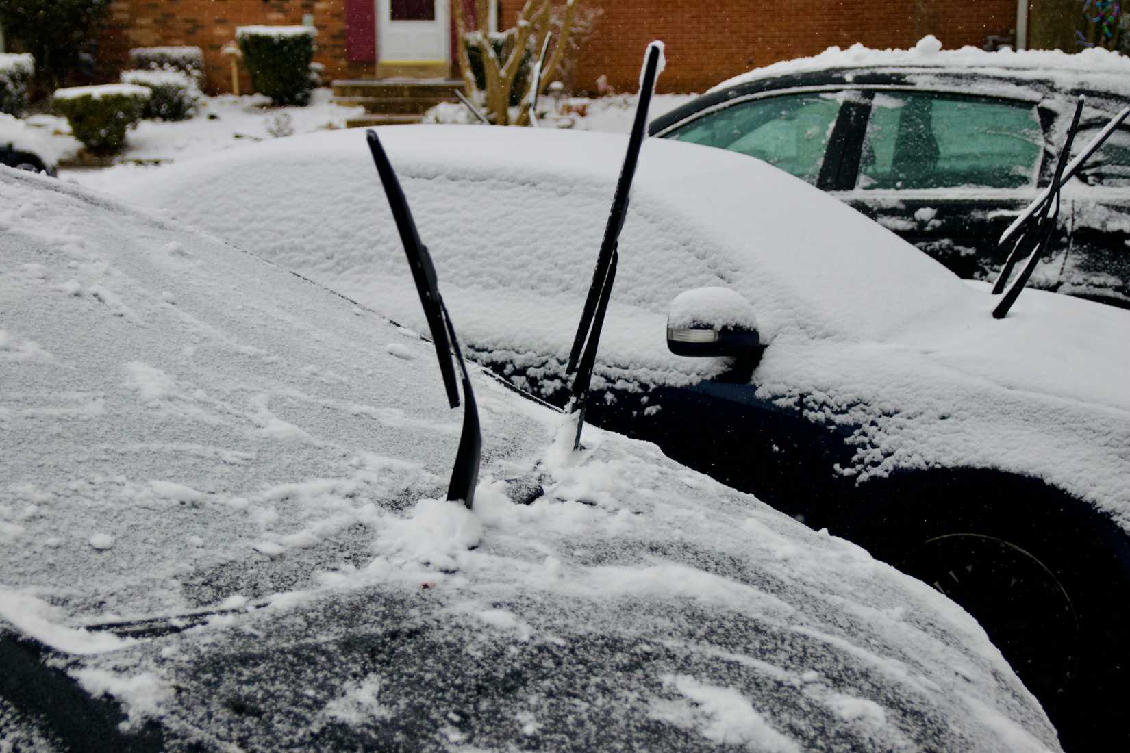 Windshield wipers tilted upward on a snow-covered car