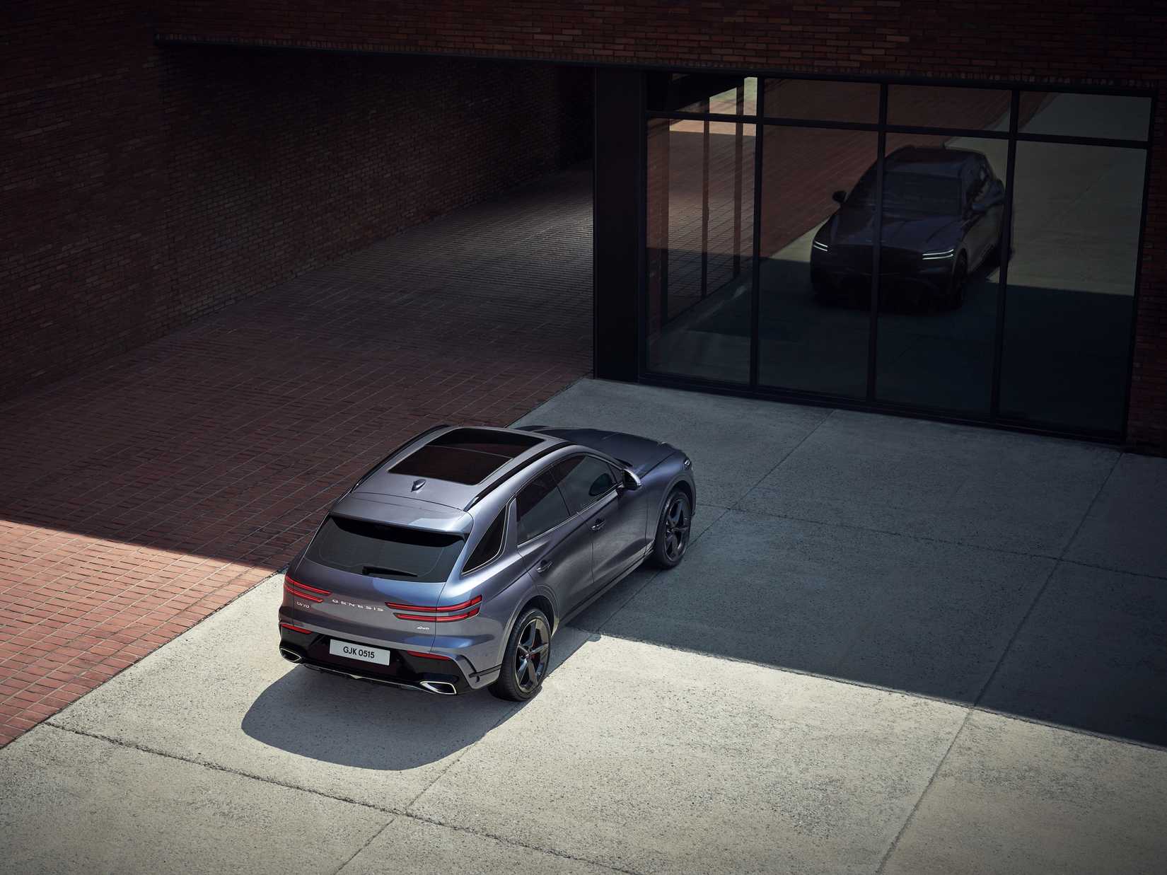 2026 Genesis GV70 parked in front a building with large front glass windows. 