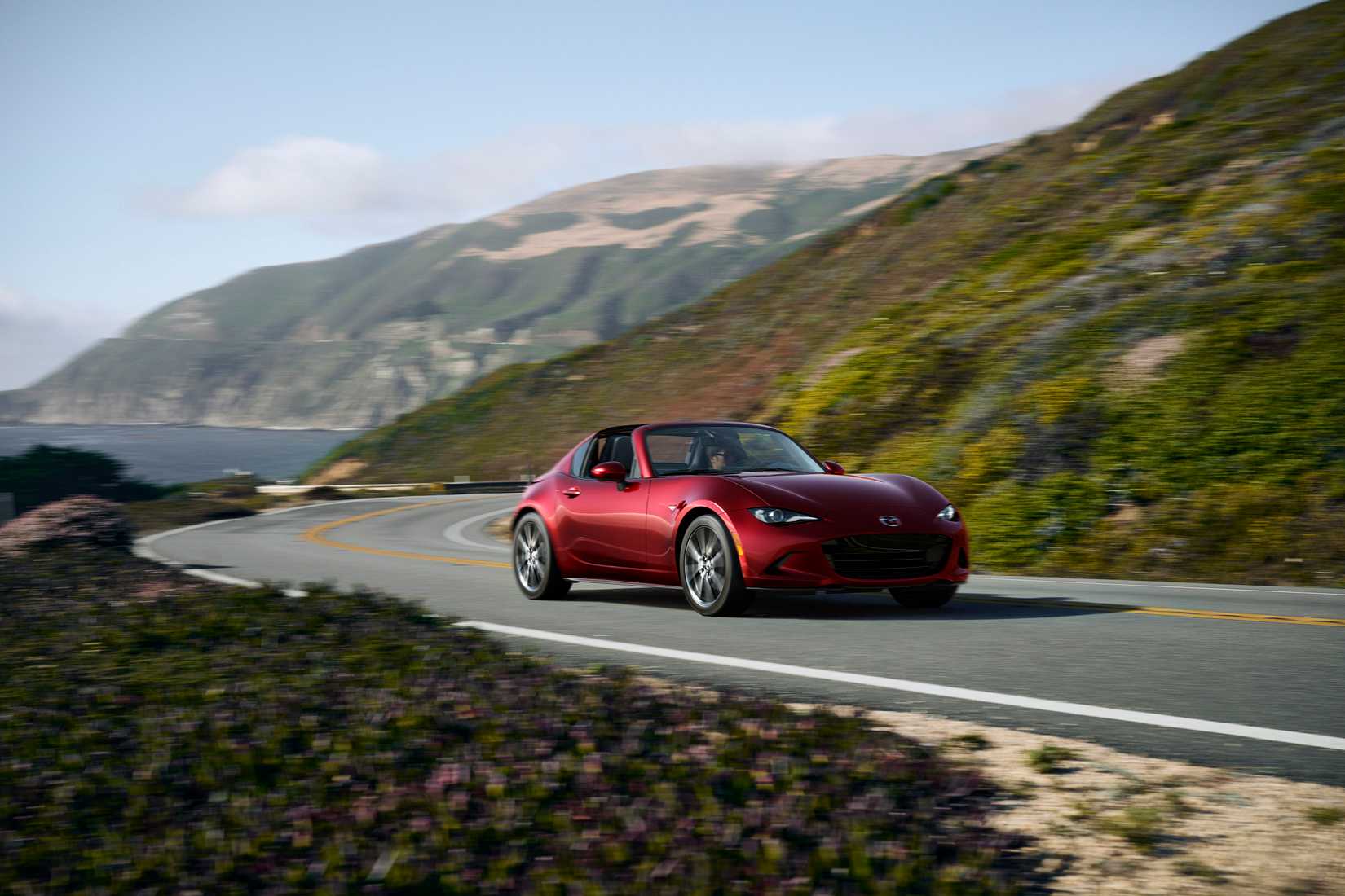 Red 2026 Mazda MX-5 Miata on a coastal highway