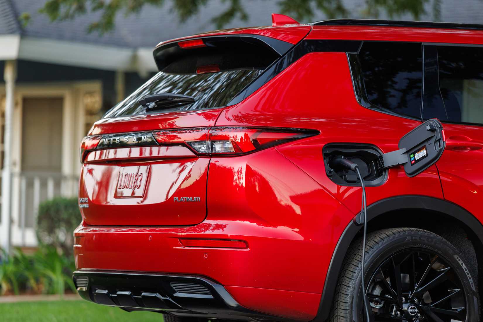 Red 2026 Nissan Rogue Plug-in Hybrid rear profile with charging cable