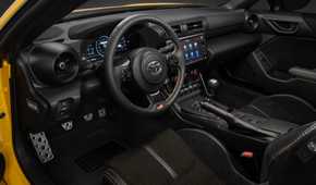 Shot inside the cabin of a yellow 2026 Toyota GR86 Yuzu, shwoing the seats and dashboard.