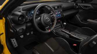 Shot inside the cabin of a yellow 2026 Toyota GR86 Yuzu, shwoing the seats and dashboard.