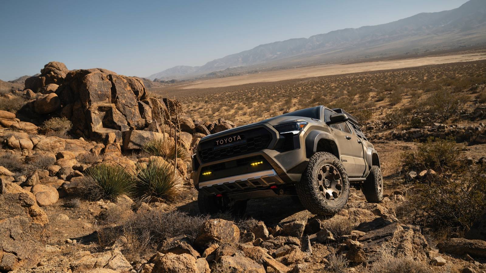 Спереди Toyota Tacoma 2026 года преодолевает валуны в движении