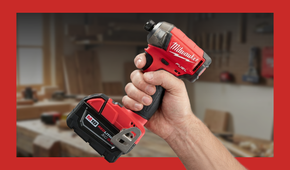 A hand holding a Milwaukee SURGE hydraulic impact driver in a workshop.
