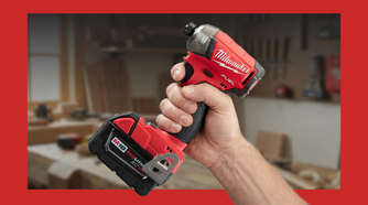 A hand holding a Milwaukee SURGE hydraulic impact driver in a workshop.