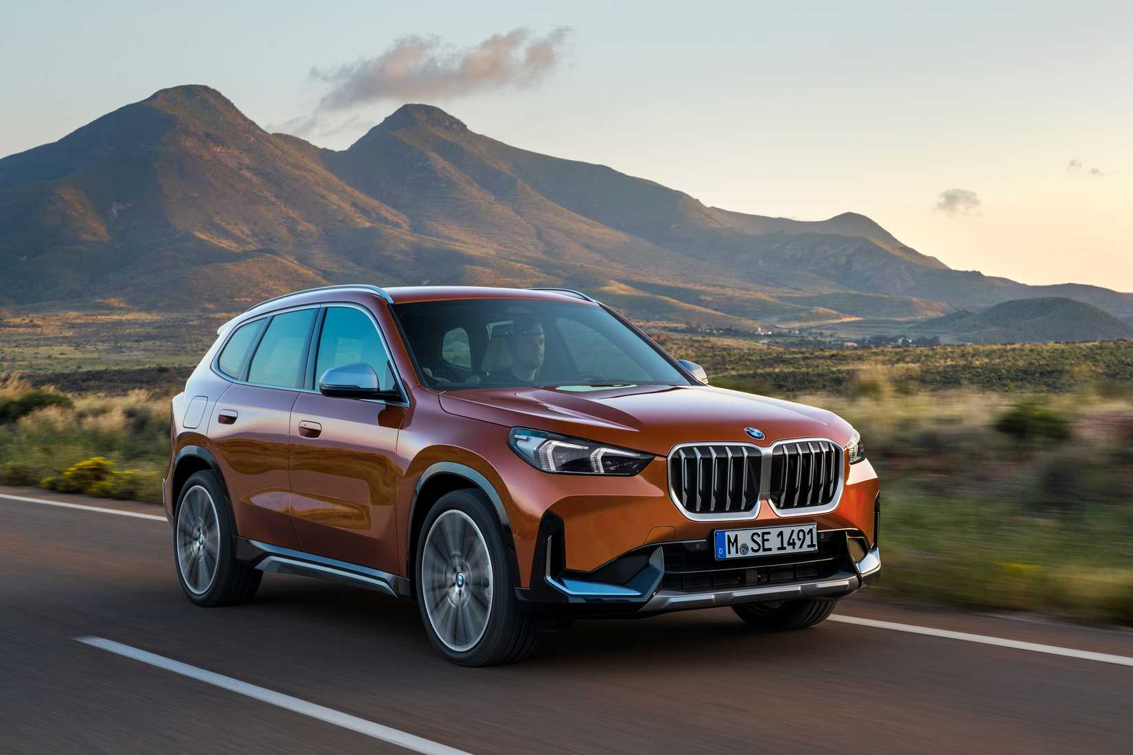 Orange BMW X1 on a scenic road in the southwest