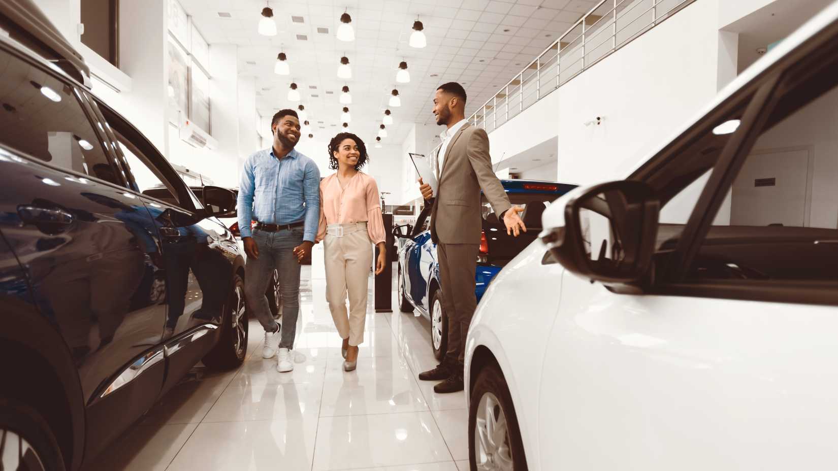 Car sales manager showing a new car to buyers in the showroom