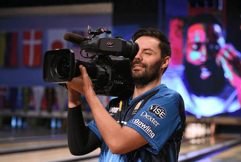 Cameraman holding a camera at a bowling alley.