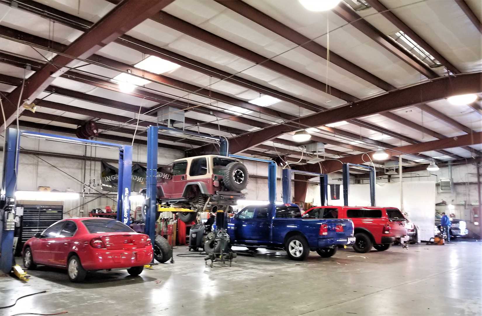Dealership service drive with multiple bays showing a Dodge Neon and Ram trucks.