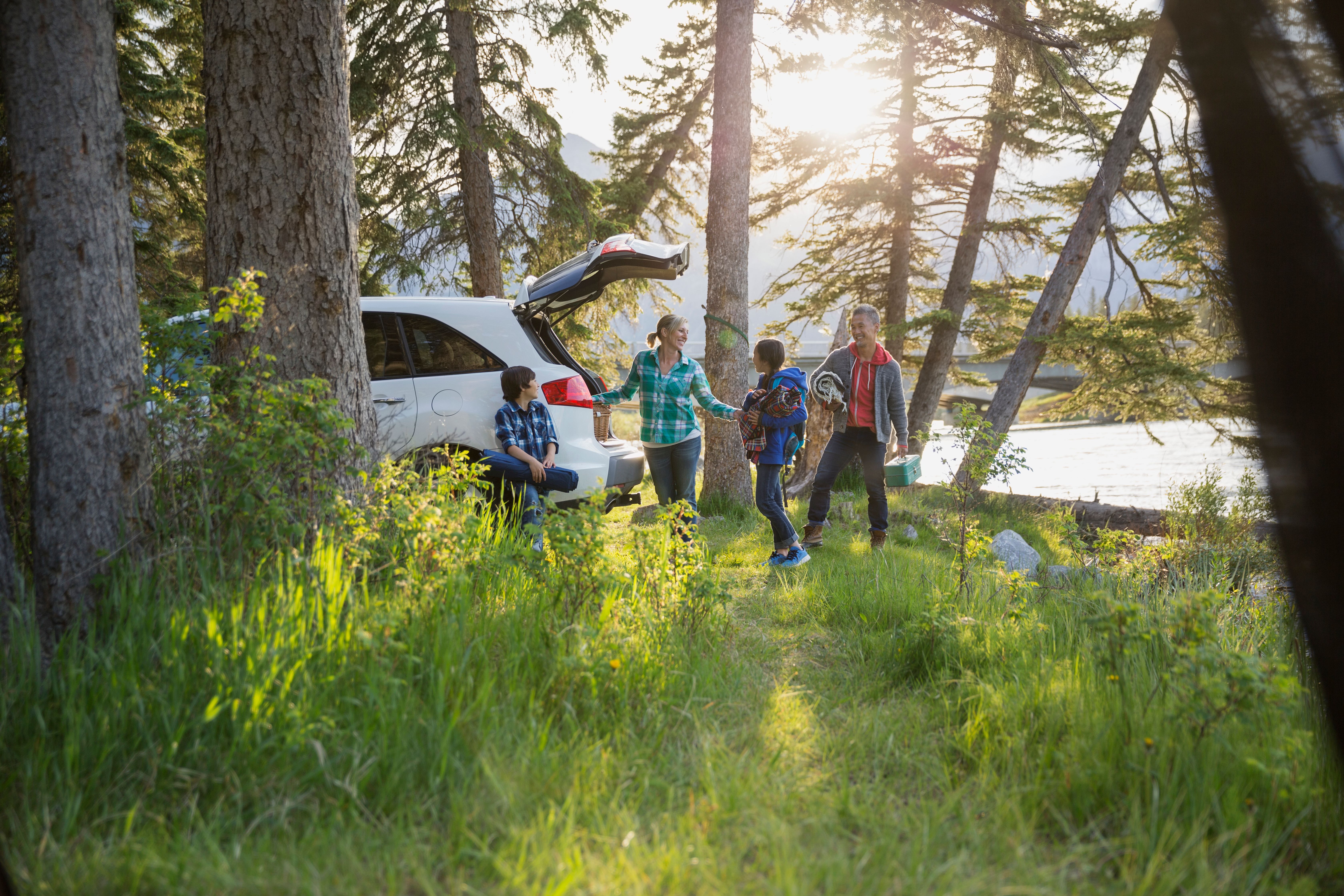 キャンプ場で車の荷解きをする家族。