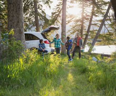 Family unpacking their car at a campsite.