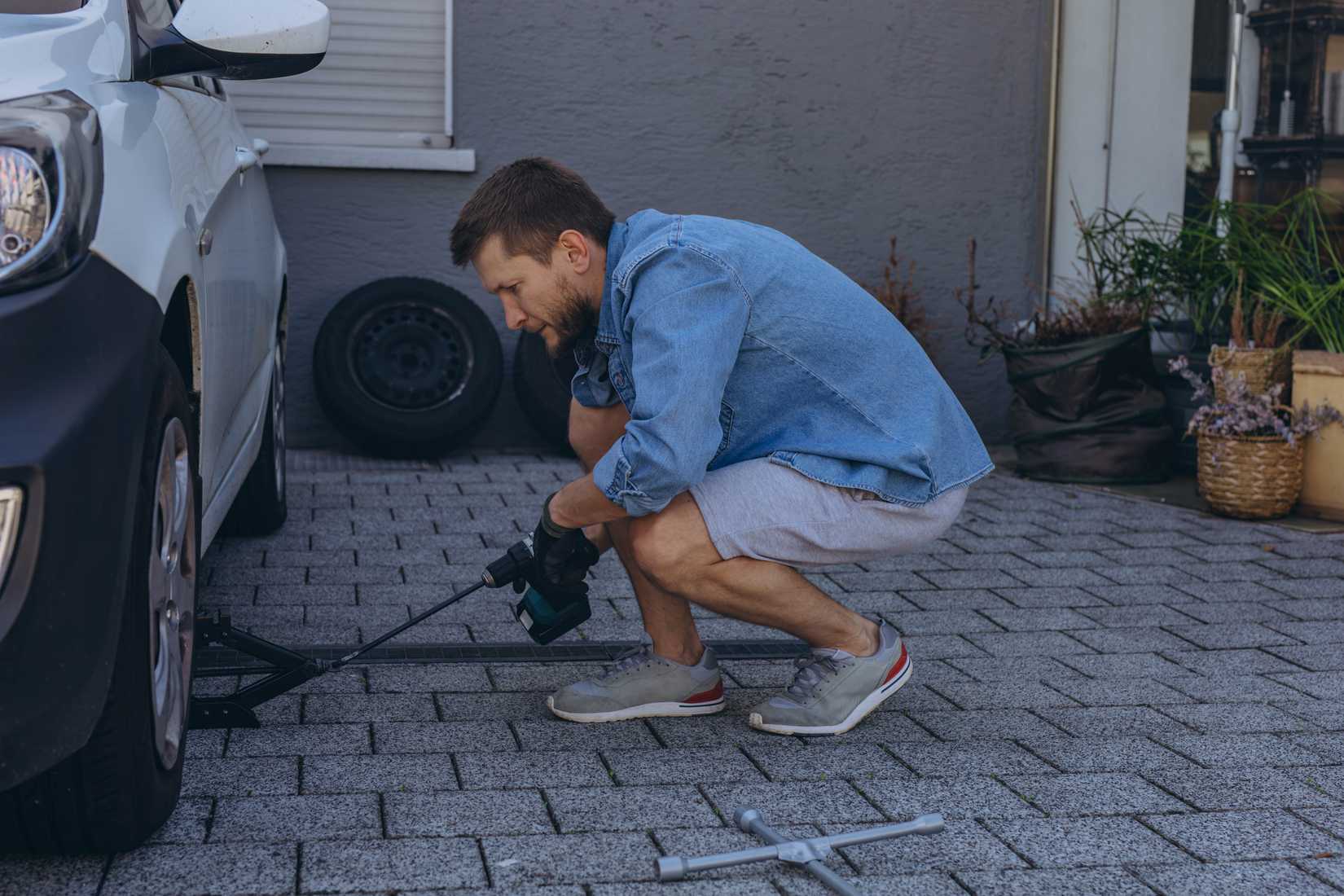 মানুষ রাস্তায় রেঞ্চ ব্যবহার করে টায়ার পরিবর্তন করছে