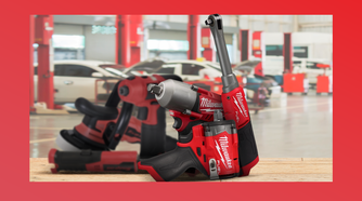 Milwaukee tools in sharp focus on a workbench, with blurred Snap-on tools and a mechanic's garage in the background.