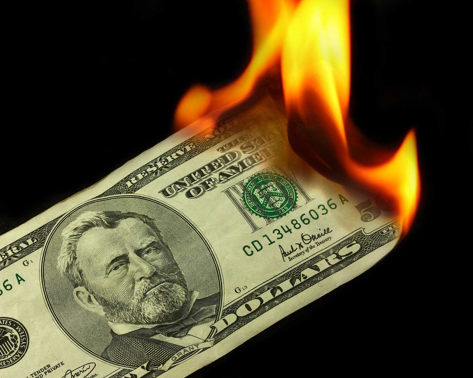 A picture of a $50 dollar bill being burned on a black background.
