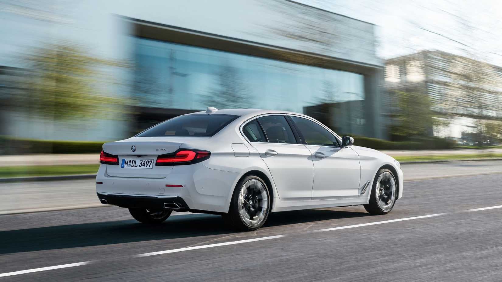 Toma dinámica de 3/4 de la parte trasera de un BMW 540i 2020 blanco.