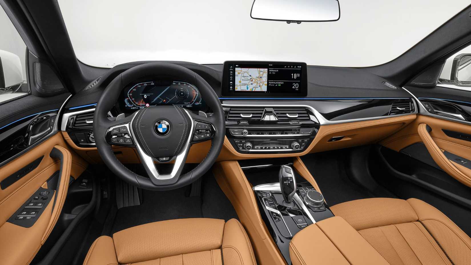 Tomada dentro de la cabina de un BMW 540i 2020, que muestra el interior de cuero color canela y el tablero.