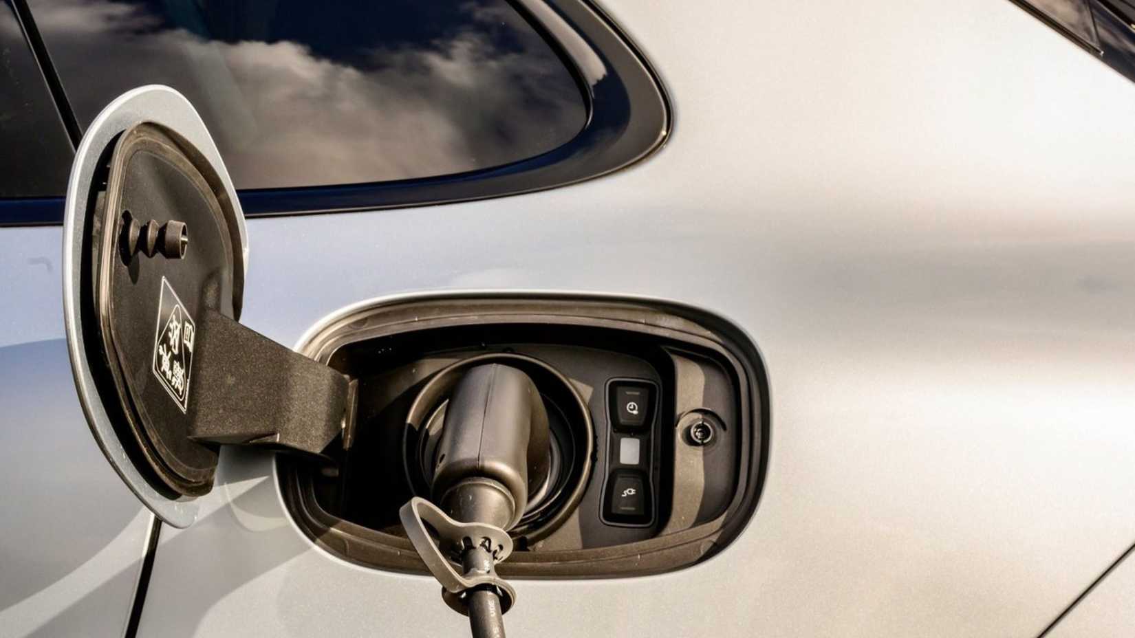 Close-up shot of the charging port with a charging cable plugged in on a silver 2020 Porsche Cayenne Turbo S E-Hybrid.