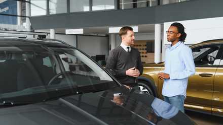 Why you will have to at all times purchase a brand new vehicle on a weekday this summer time Sales consultant with a customer on the showfloor at a car dealership