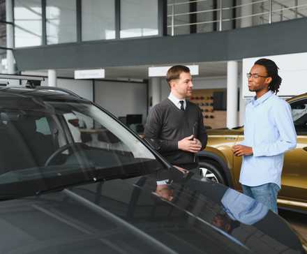 Sales consultant with a customer on the showfloor at a car dealership