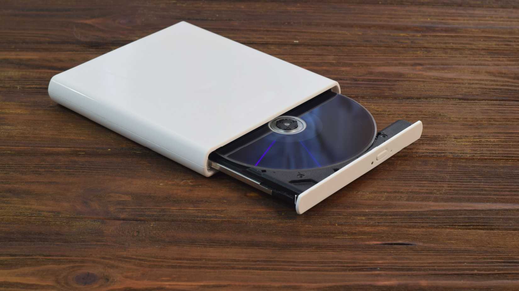 A PC external optical drive sitting on a wooden surface.