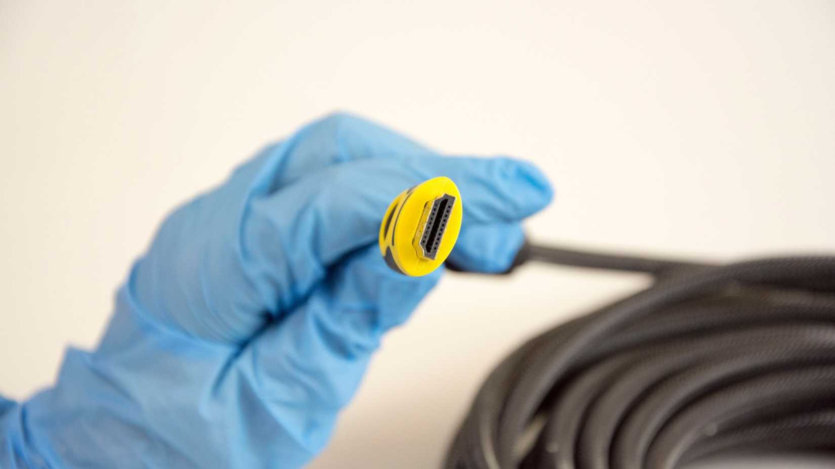 A gloved hand holds the end of a very long HDMI cable.