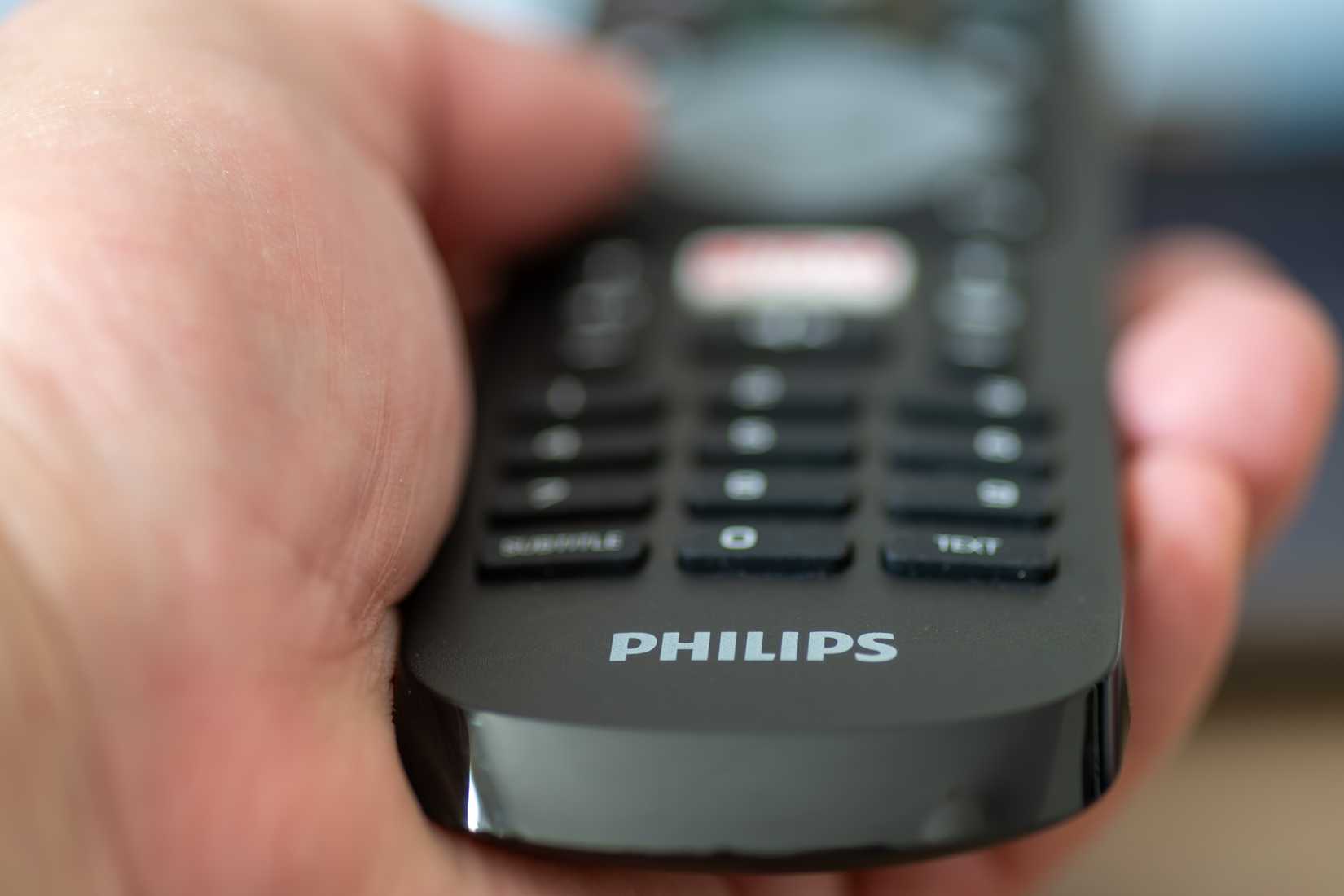A Philips TV remote held in someone's hand.
