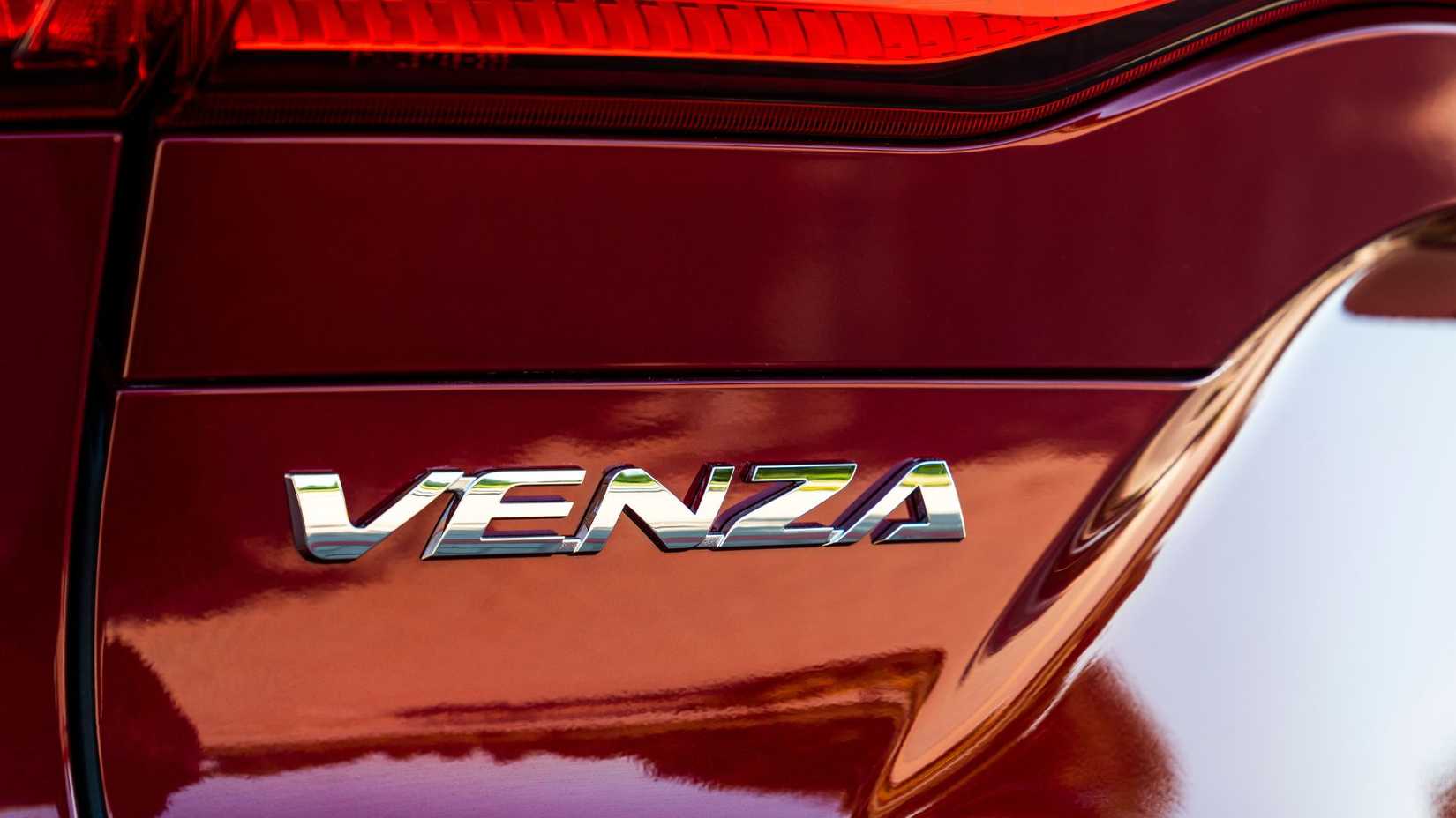 Close-up shot of the badging on the trunk lid of a red 2022 Toyota Venza LE.