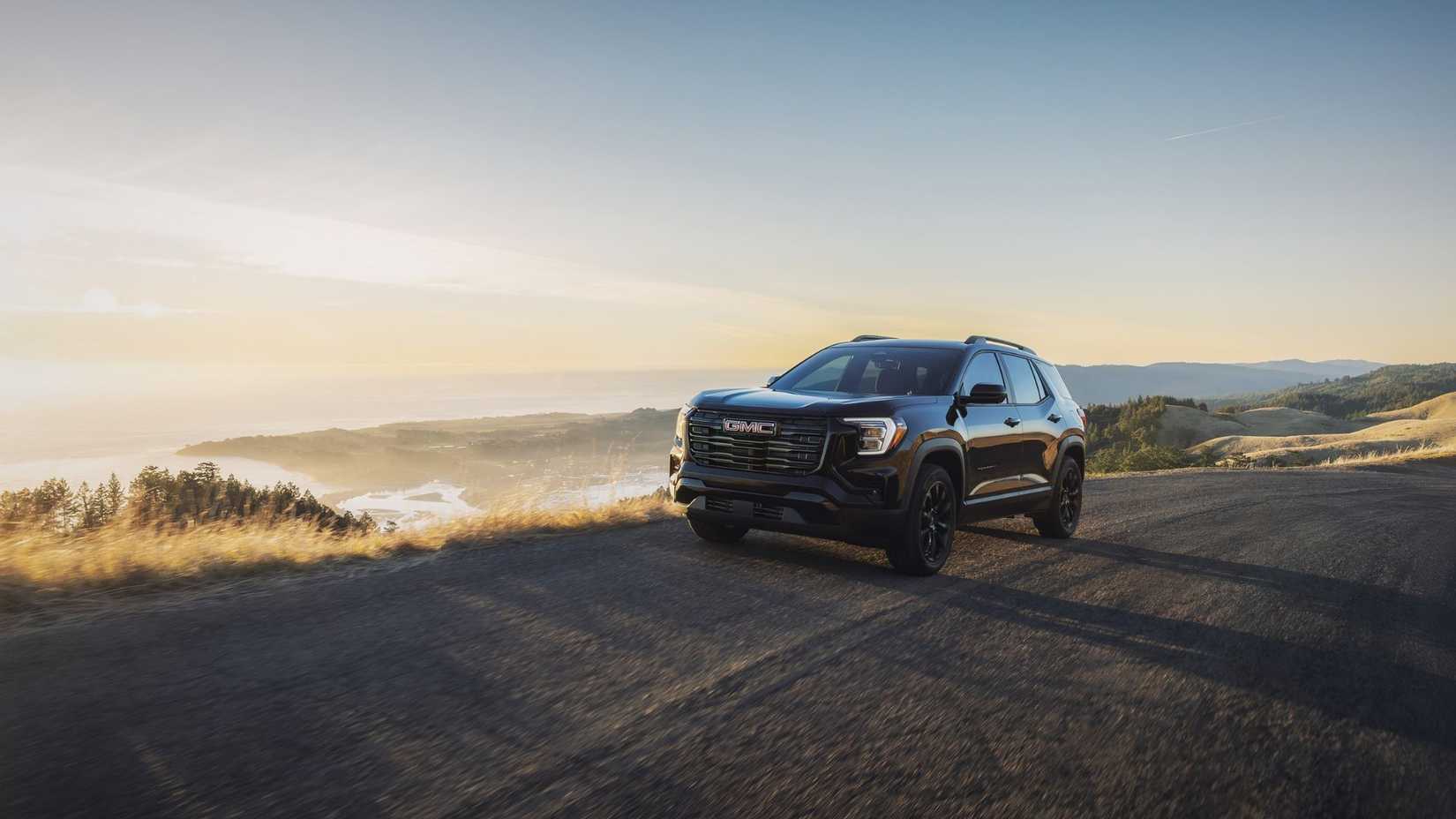 Front 3/4 view of the 2026 GMC Terrain Elevation in Twilight Ebony Metallic with the Black Edition Package driving on a highway.