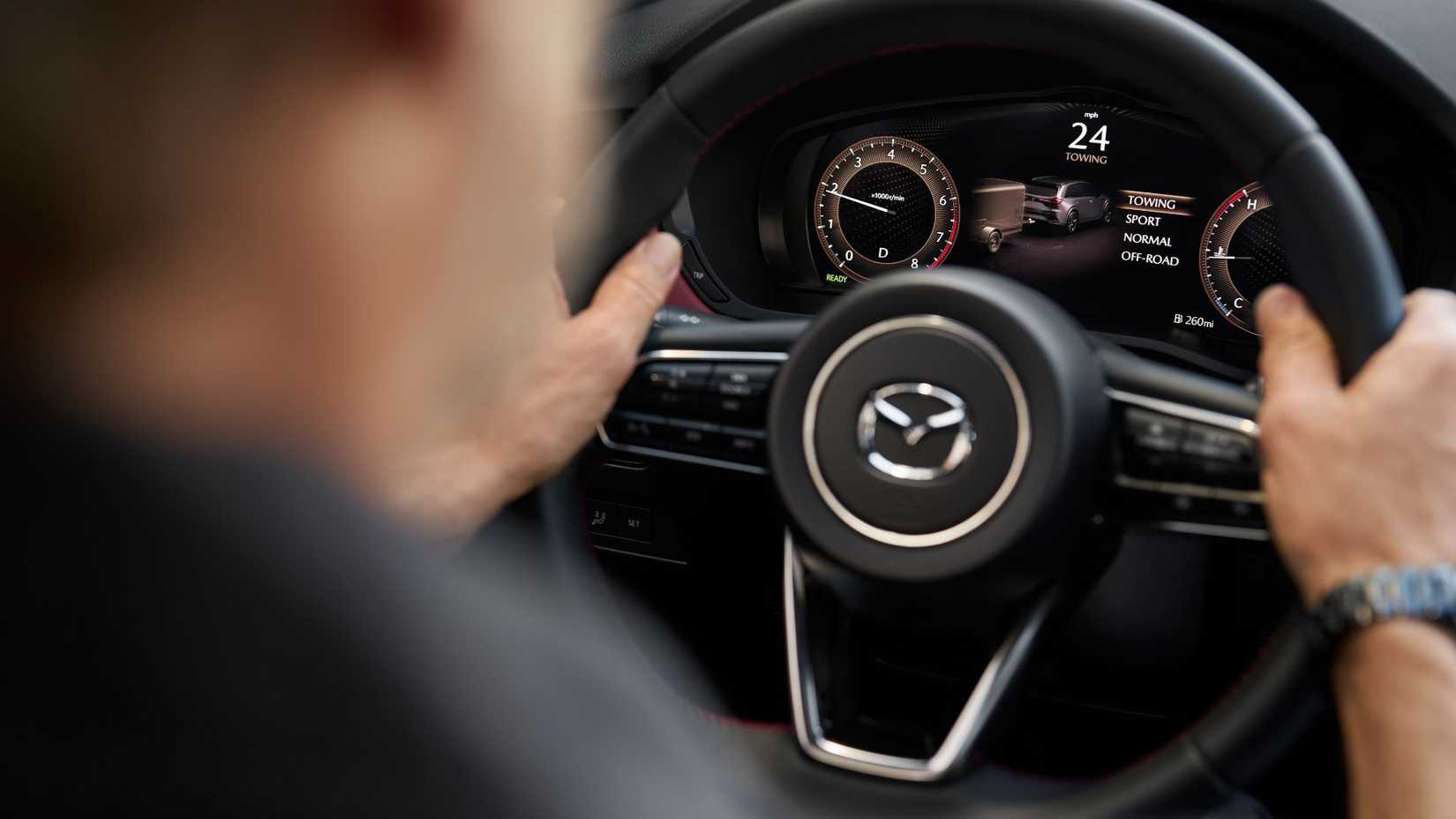 Close-up shot of a male driver behind the wheel of a 2026 Mazda CX-70.