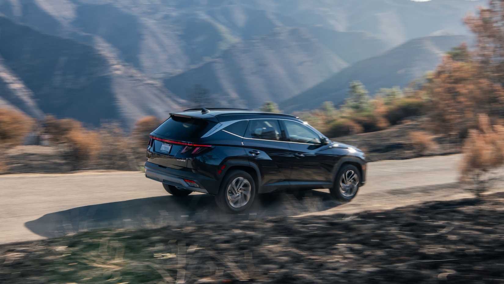 Dynamic rear 3/4 shot of a black 2026 Hyundai Tucson Hybrid.