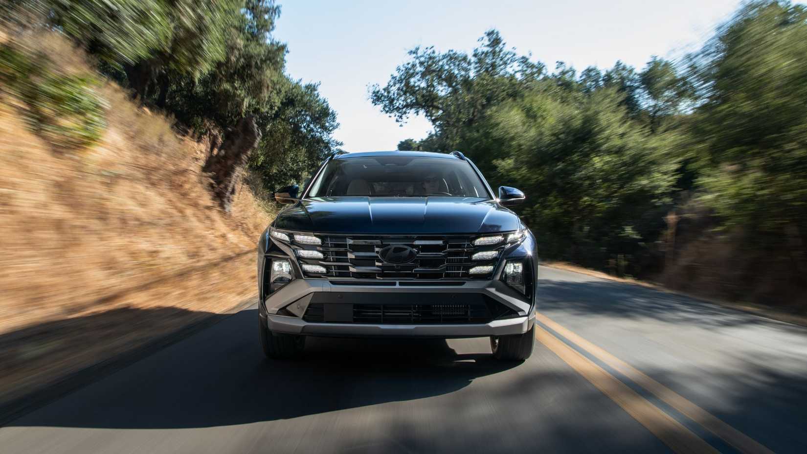 Dynamic front-end shot of a black 2026 Hyundai Tucson Hybrid.