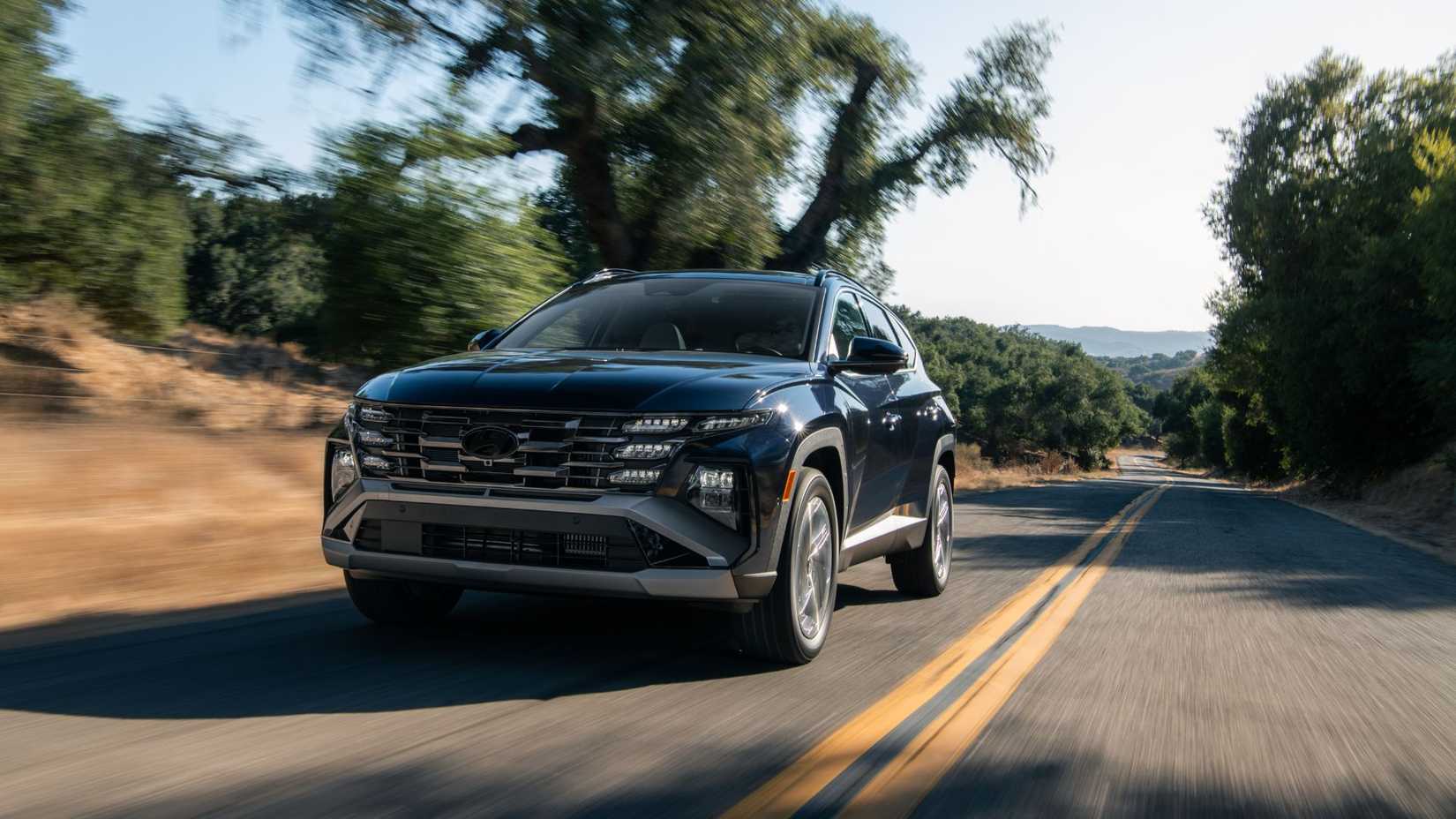 Dynamic front 3/4 shot of a blue 2026 Hyundai Tucson Hybrid.