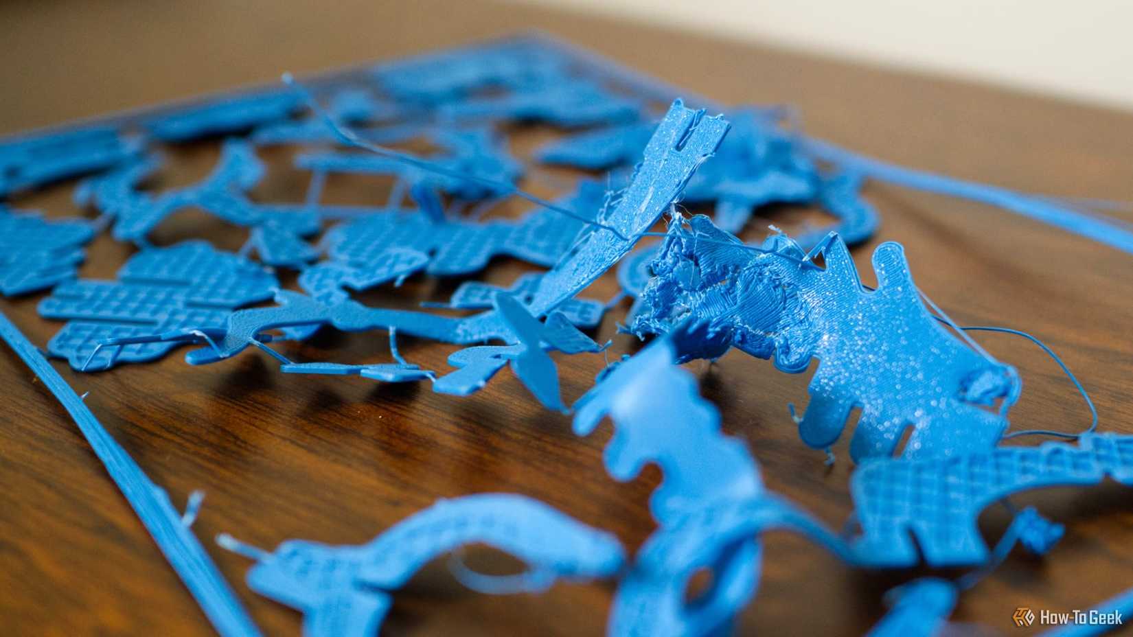 A failed blue 3D print destroyed on a desk.