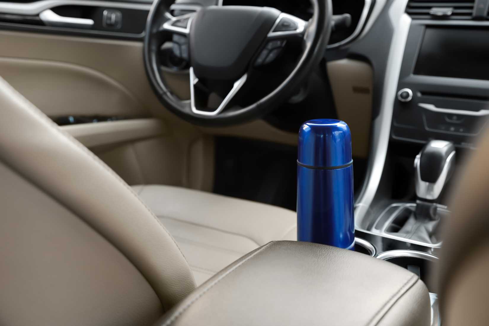 Blue thermos inside beige car close-up