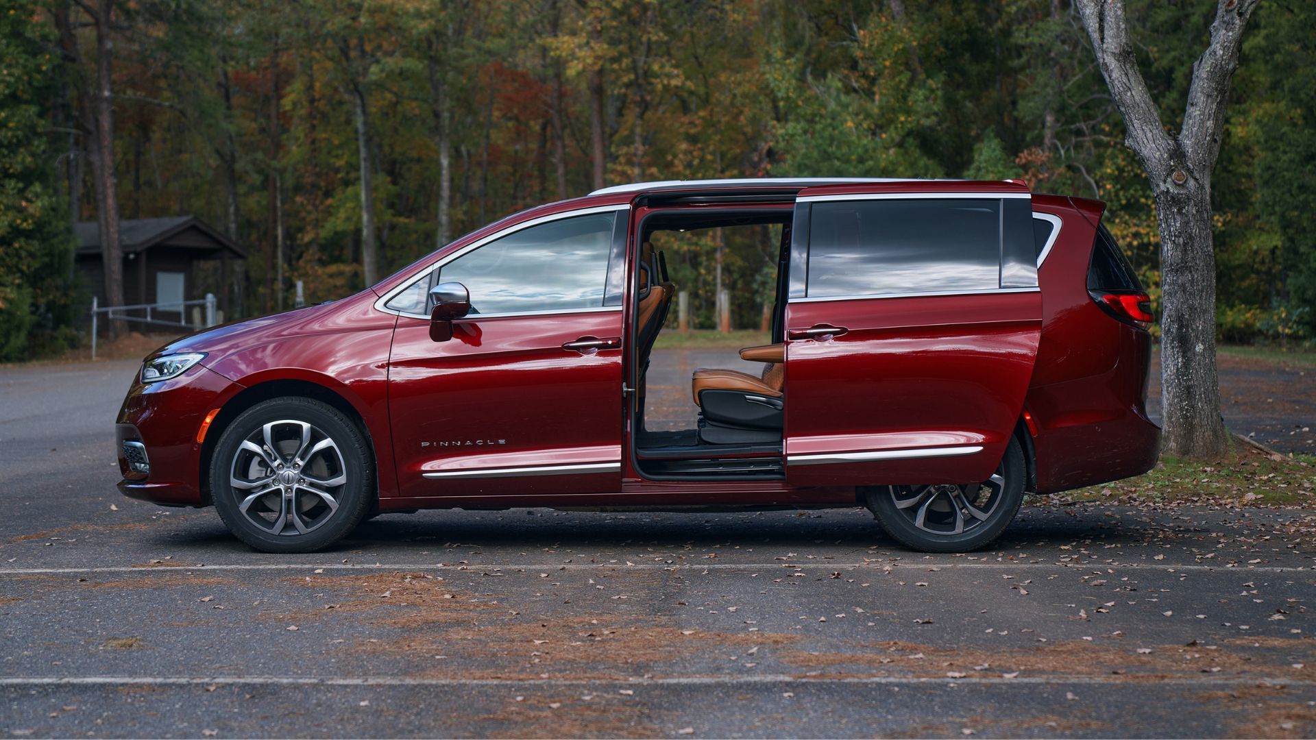 Static side profile shot of a red 2022 Chrysler Pacifica Pinnacle with its sliding door open.