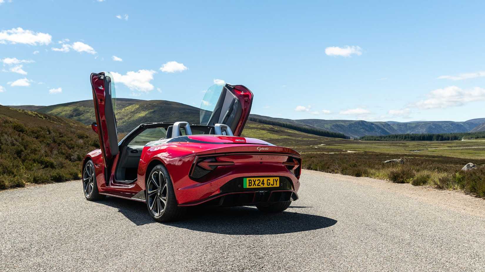 Static rear 3/4 shot of a red MG Cyberster with its doors raised.