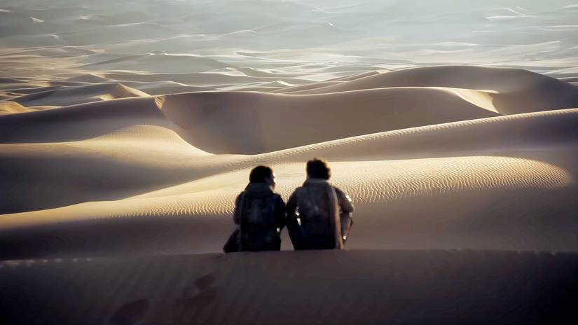 Paul and Chani in Dune: Part 2 sitting on a sand hill. 