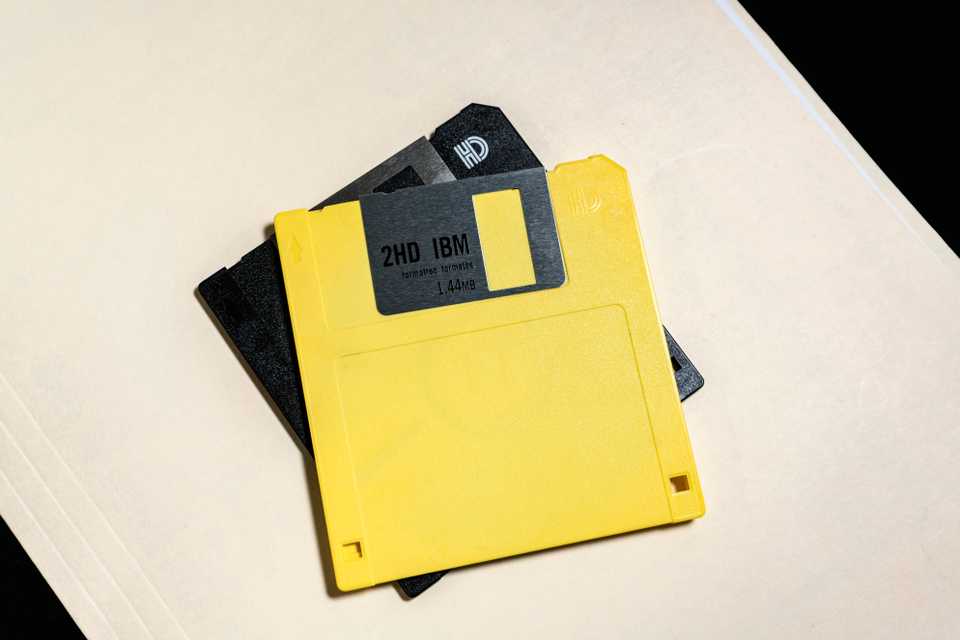 A high-density yellow floppy disk sits on top of a black floppy disk.