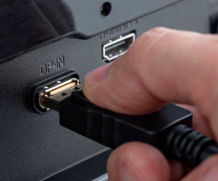 Close-up of a hand plugging a DisplayPort cable into the connector.