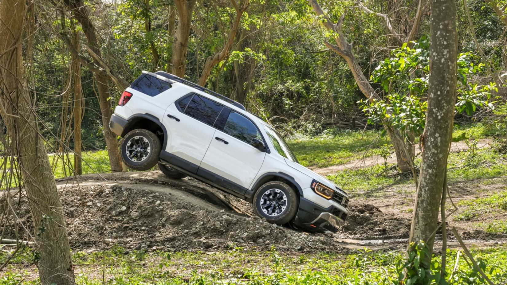 Dynamic side profile shot of a white 2026 Honda Passport TrailSport Elite off-roading.