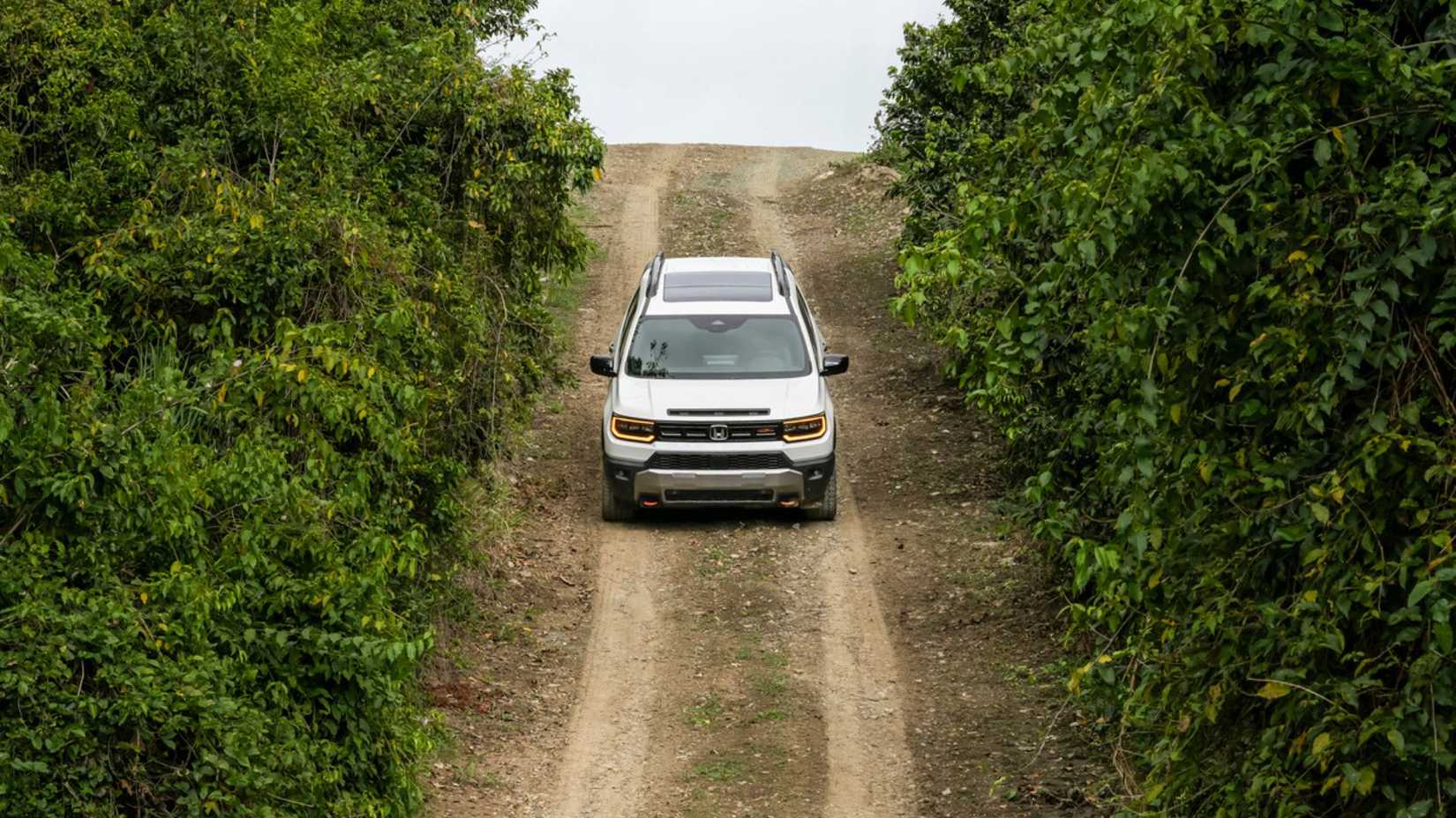 Dynamic front-end shot of a white 2026 Honda Passport TrailSport Elite off-roading.