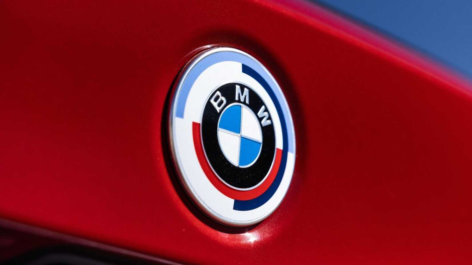 Close-up shot of the BMW badge on the trunk lid of a red 2023 BMW M340i.