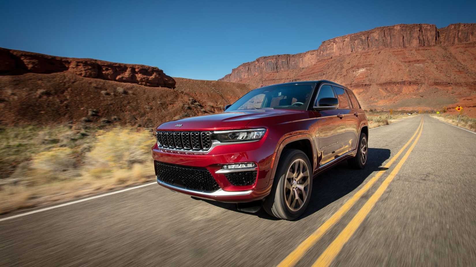 Dynamic front 3/4 shot of a red 2025 Jeep Grand Cherokee Summit Reserve.