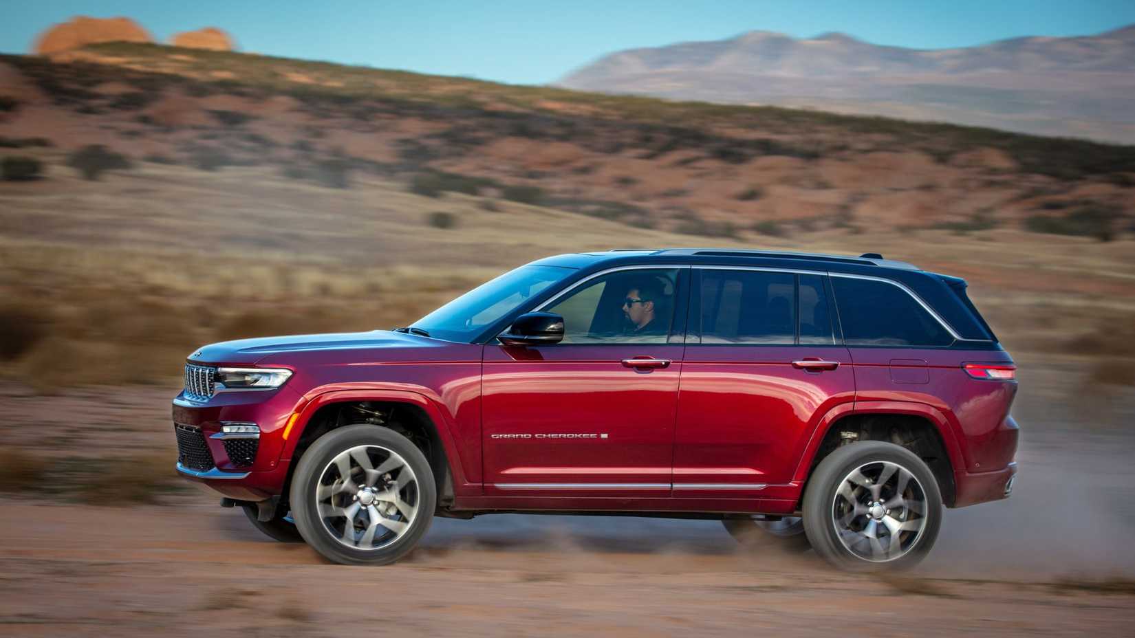 Dynamic side profile shot of a red 2025 Jeep Grand Cherokee Summit Reserve.