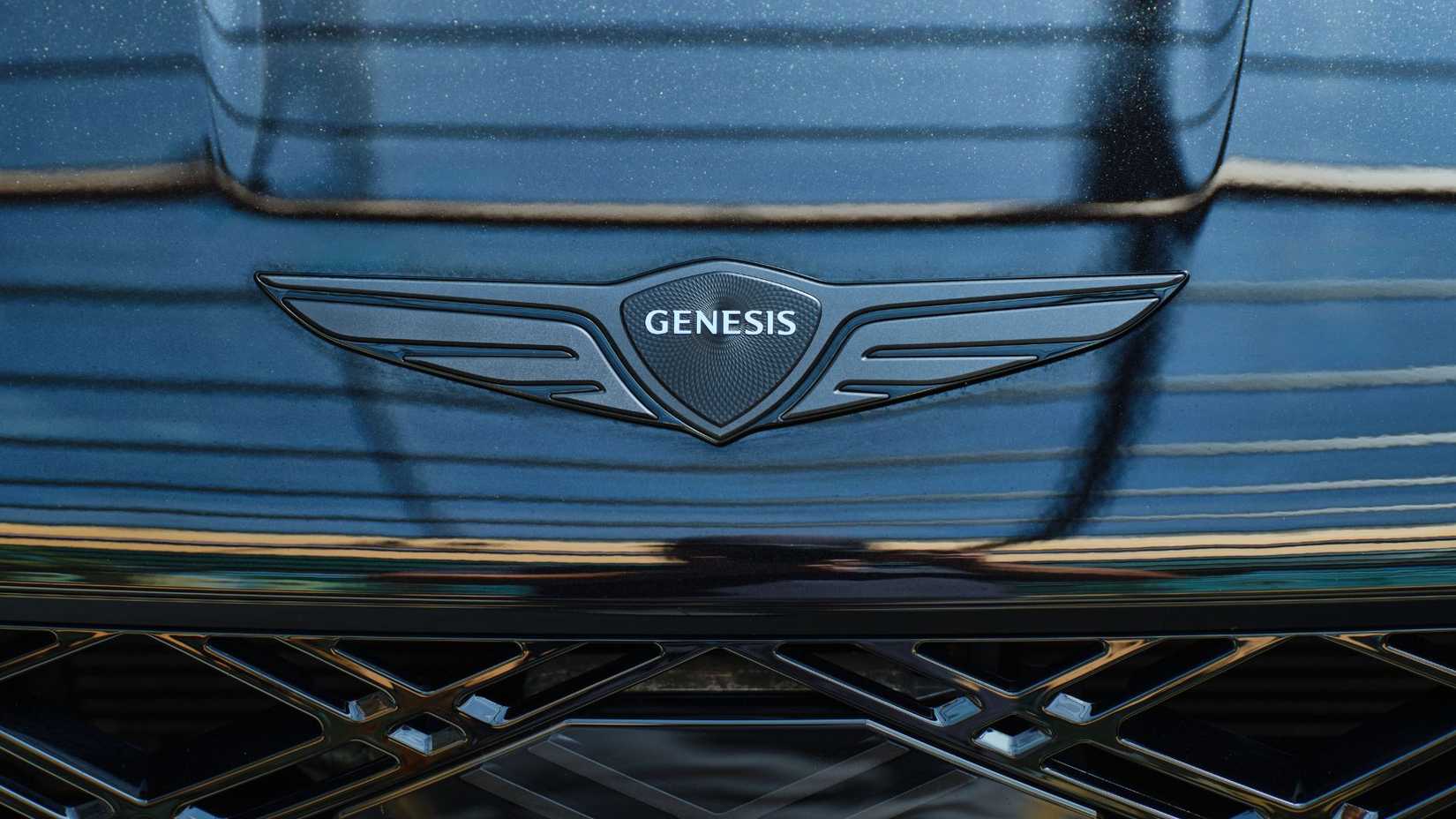 Close-up shot of the Genesis badge on the hood of a black 2026 Genesis G80 Prestige Black.