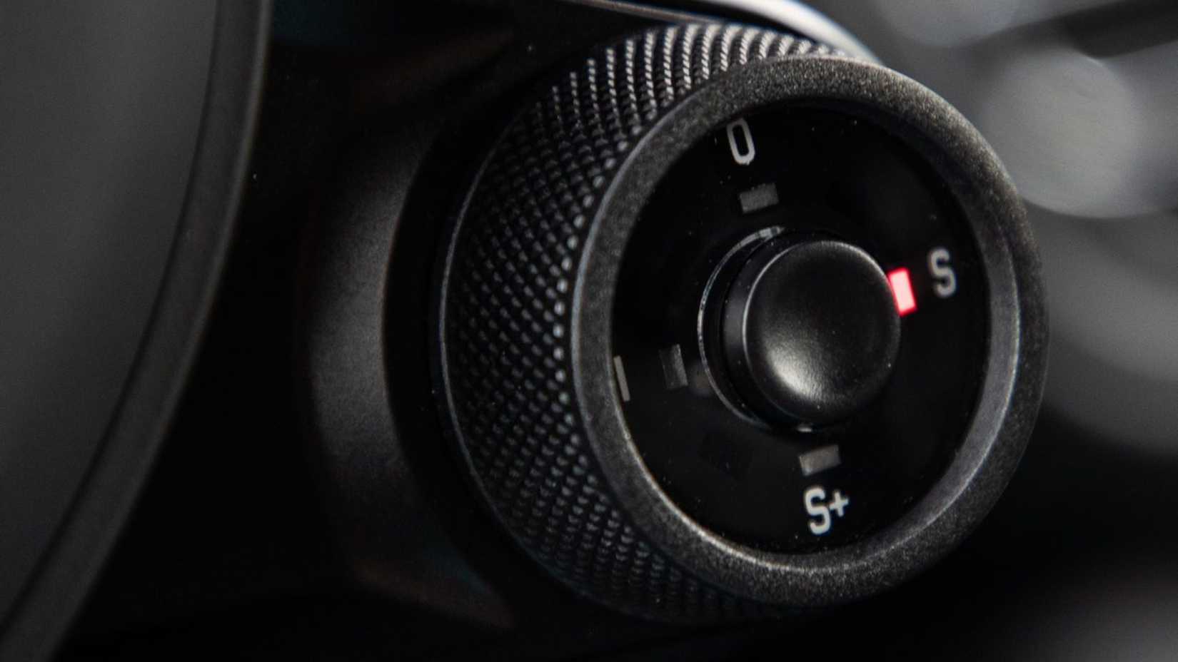 Close-up shot of the driving mode switch on the steering wheel of a 2019 Porsche Macan Turbo.