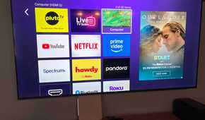 An image of a 75" Roku TV open to the home page and a Mini PC underneath it. The home screen has computer highlighted